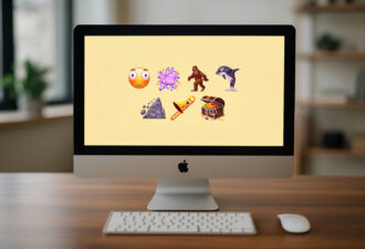 iMac на дерев’яному столі в офісі; на екрані — нові емодзі Unicode 17.0: перекошене обличчя, хмара бійки, косатка, волохате створіння, зсув, тромбон і скриня зі скарбами; попереду клавіатура й миша.