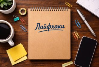 Закритий крафтовий блокнот із написом «Лайфхаки» на обкладинці лежить на дерев’яному столі, навколо розкидані кольорові скріпки, стікери, рулон скотчу, ручка та чашка кави, вид зверху.